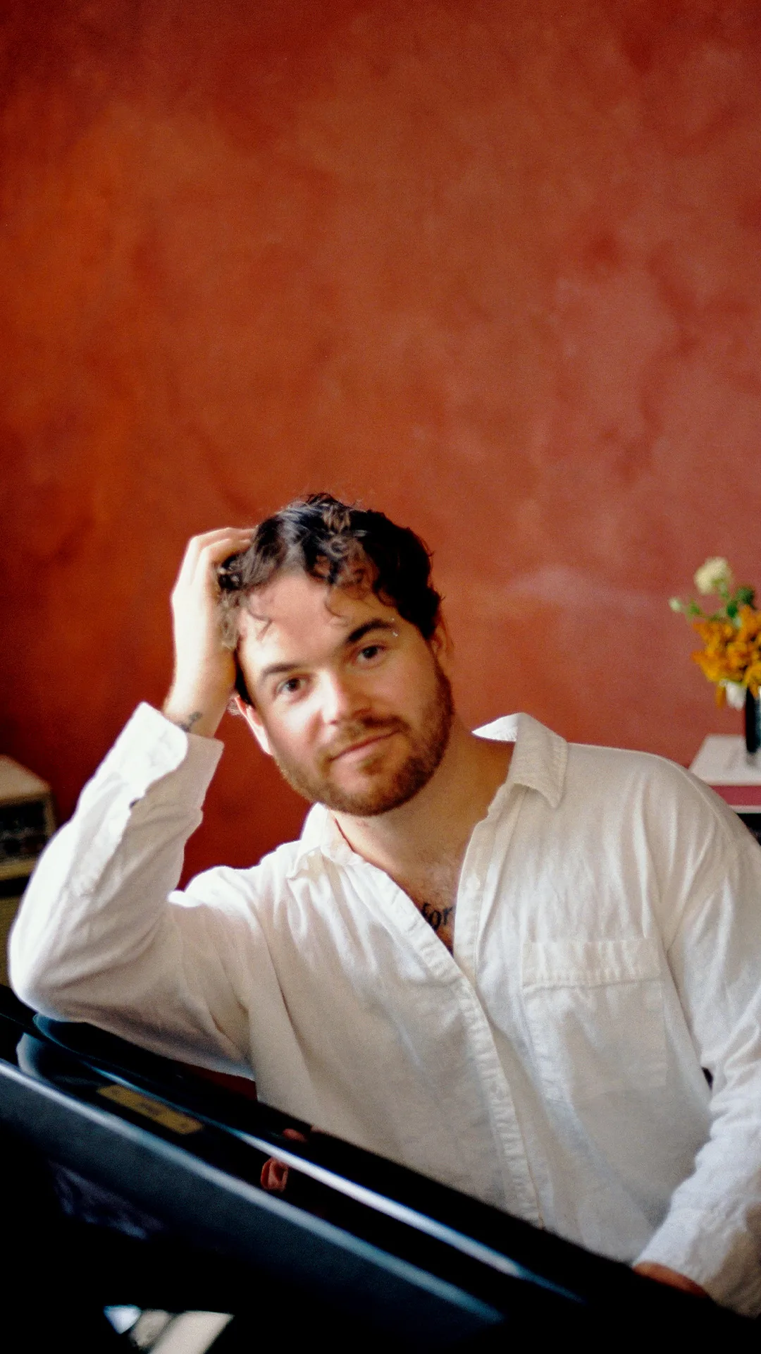 Conor Thaxter at the piano, smiling, one hand in his hair