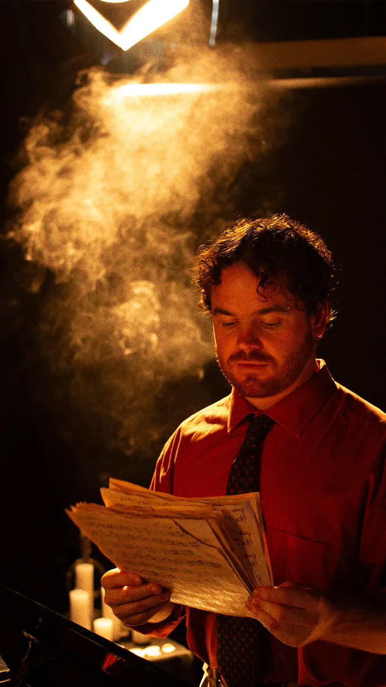 Conor Thaxter reading sheet music under a stage light